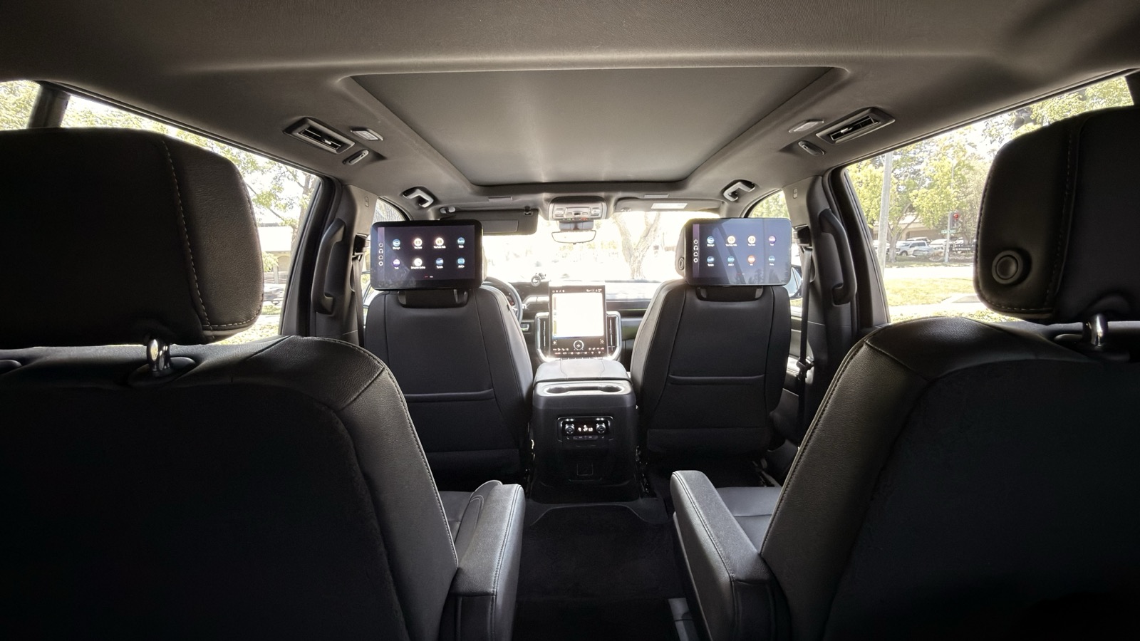 Spacious rear cabin of an executive SUV with dual entertainment screens and black leather seats