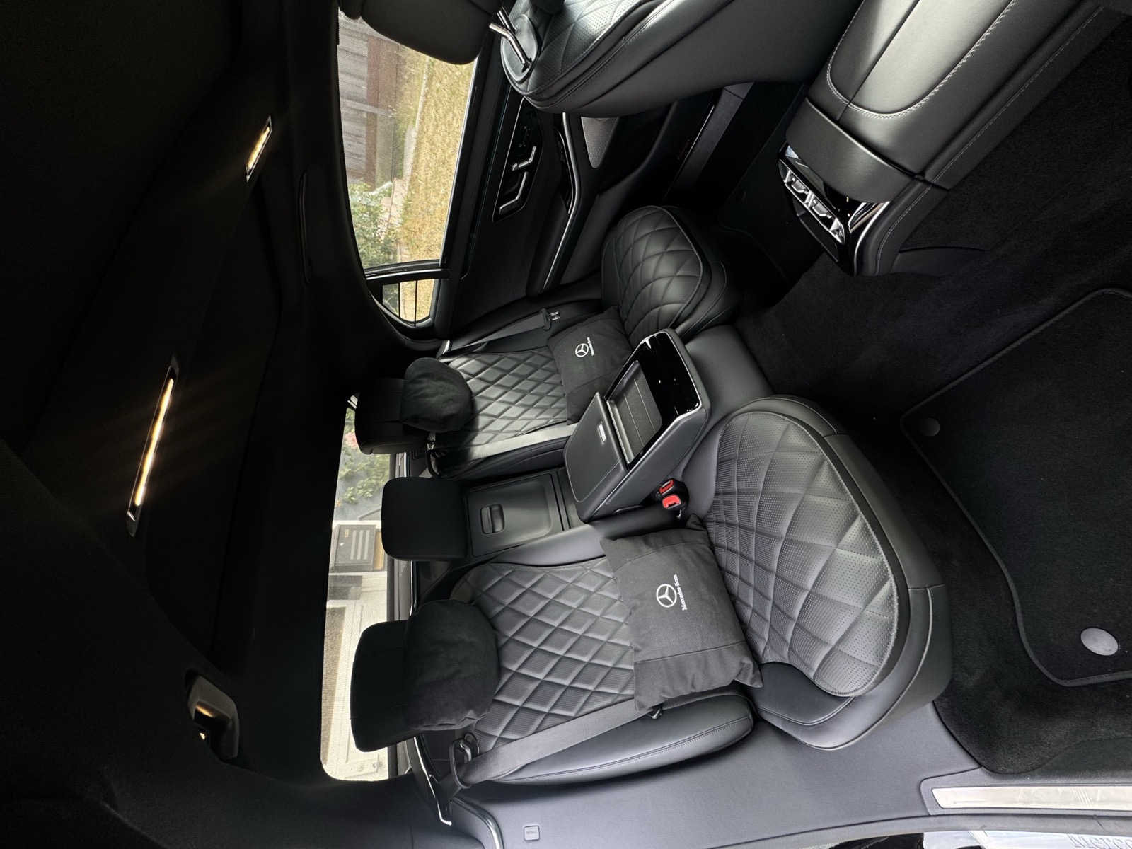Diamond-quilted rear seats of a Mercedes-Benz sedan with branded pillows