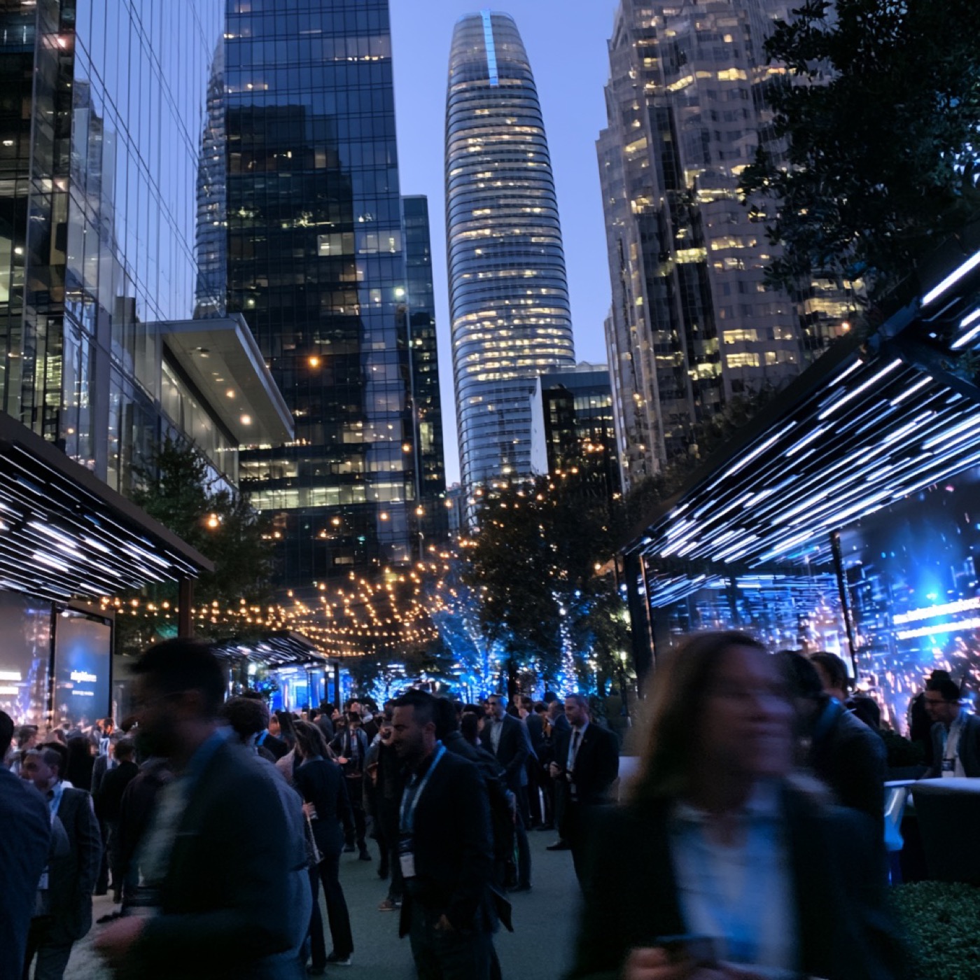 Dreamforce attendees gathered beneath the Salesforce Tower at dusk