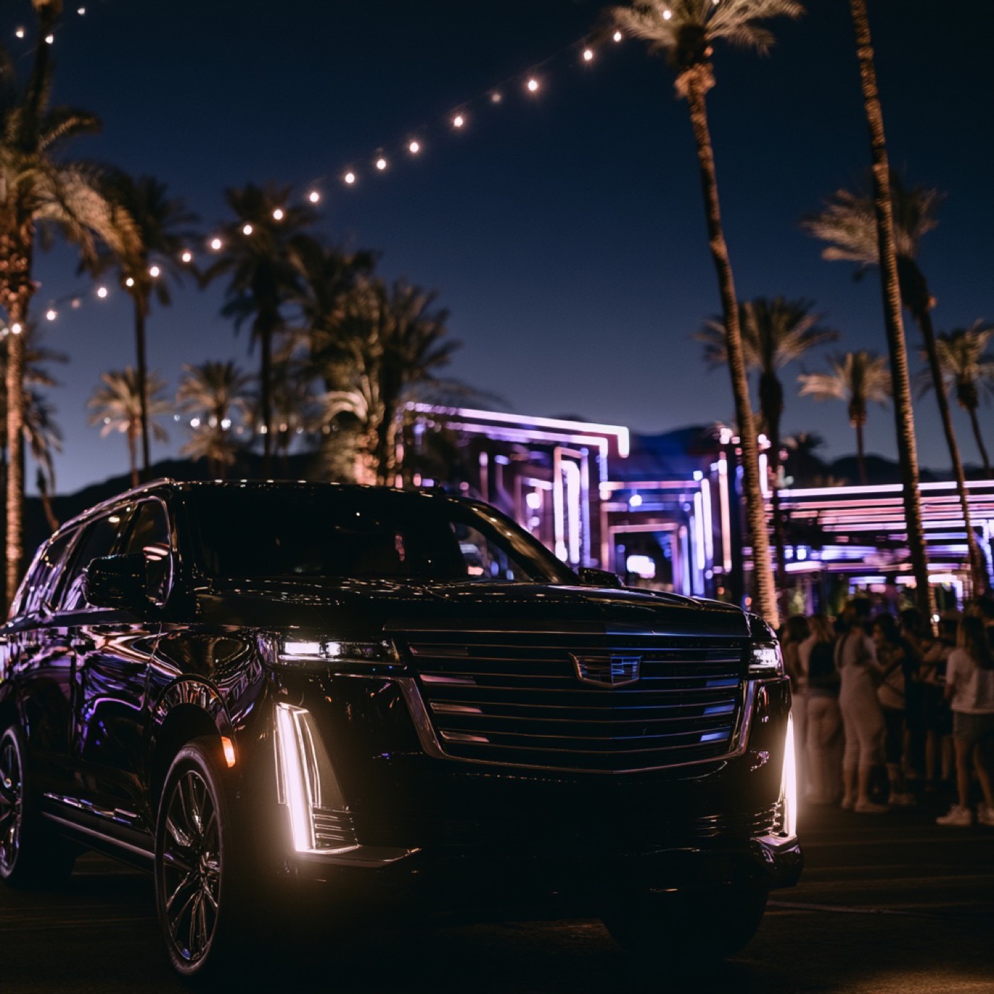 Black Cadillac Escalade waiting by palm trees and festival lights at night