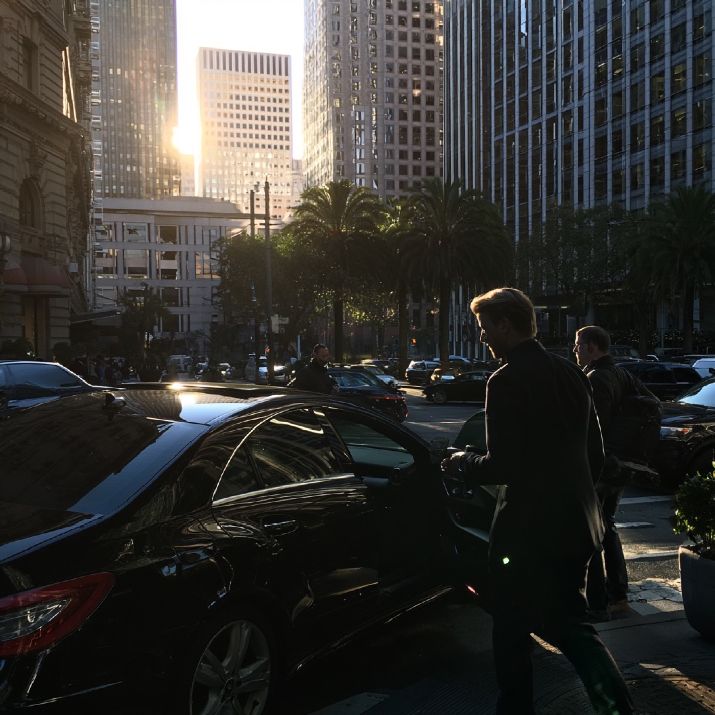Executive stepping into a black sedan on a downtown San Francisco street at golden hour