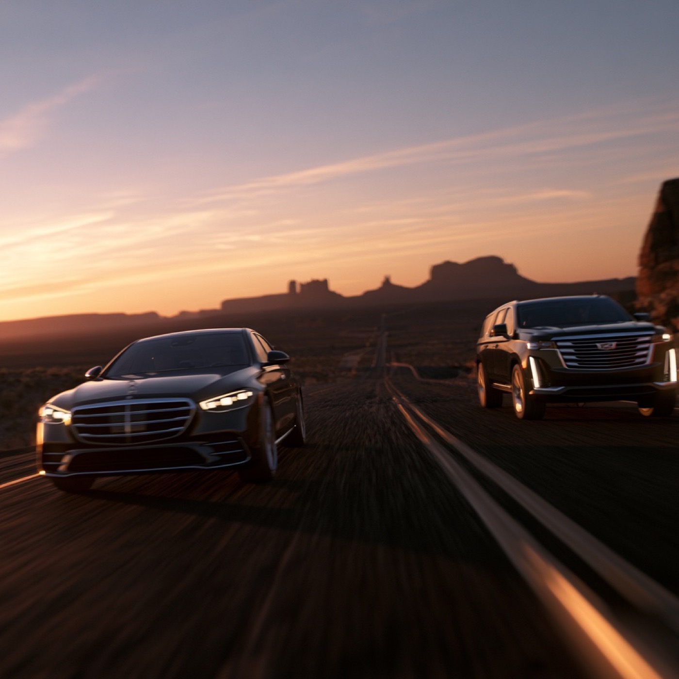 Black Mercedes sedan and Cadillac Escalade on an open highway at sunset